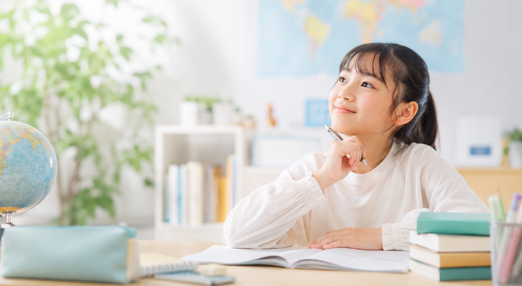 地球儀と世界地図を前に、英語の勉強をしながら夢を見つめる生徒
